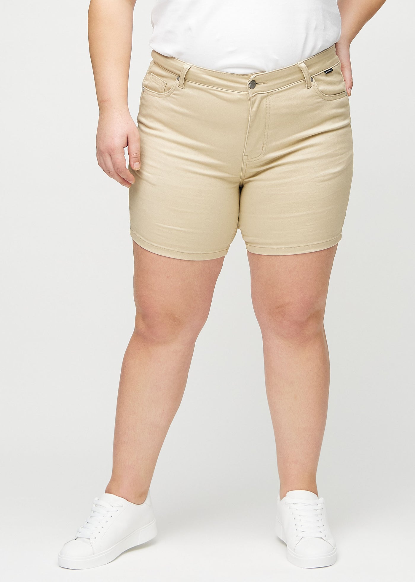 Beige skinny short shorts, modelnavn Gazelles, som sidder tæt til, og slutter midt på låret på en plus-size model, set forfra.