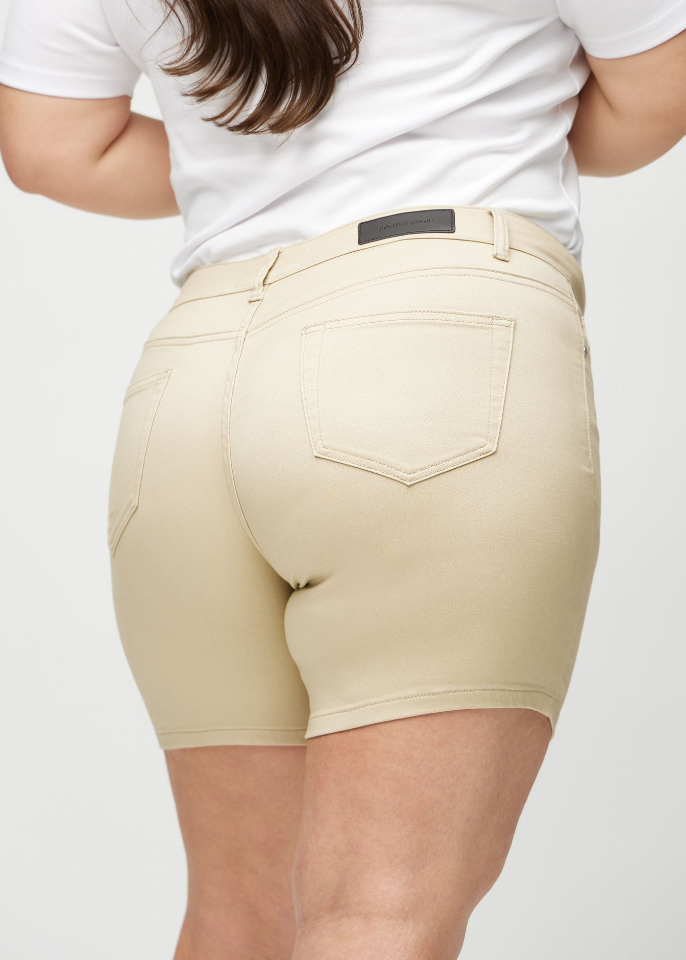 Beige skinny short shorts set bagfra tæt på en plus-size model for at vise detaljer.