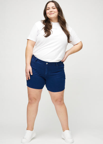 Fuldt billede af en plus-size model i mørkeblå skinny short shorts.