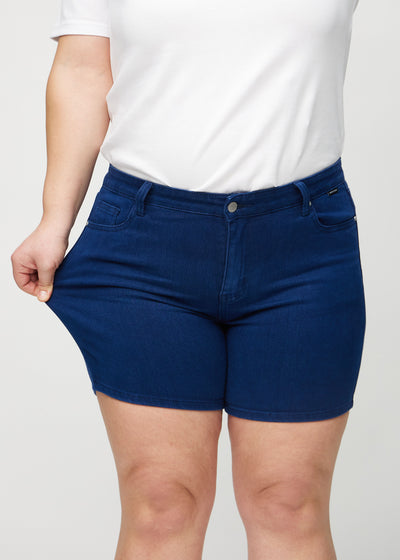 Plus-size model strækker shortsene ved låret for at vise stretch.