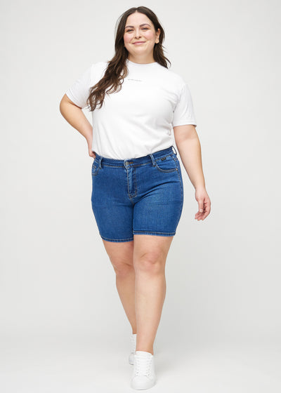 Fuldt billede af en plus-size model i mørk denim skinny short shorts.