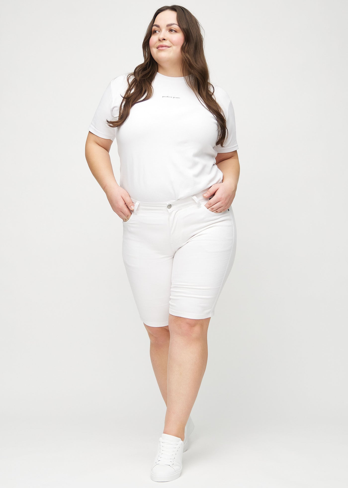 Fuldt billede af en plus-size model i hvide skinny middle shorts.