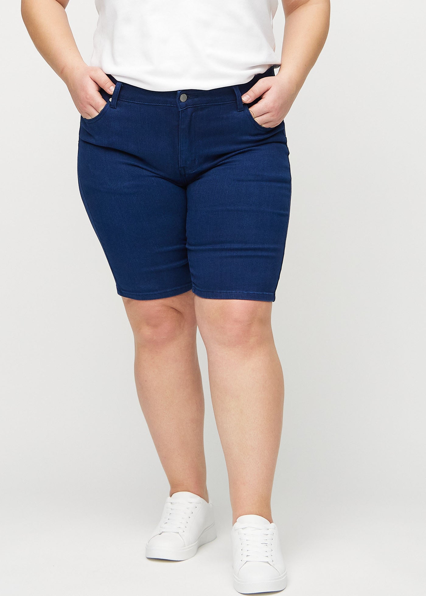 Mørkeblå skinny middle shorts, modelnavn Royals, som sidder tæt til låret og slutter lige over knæet på en plus-size model, set forfra.