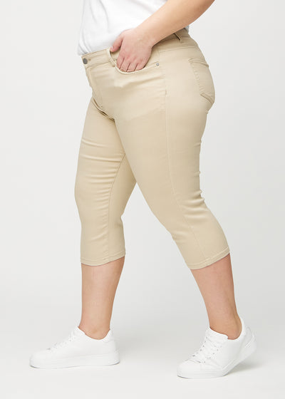 Beige skinny capris set fra siden på en plus-size model.