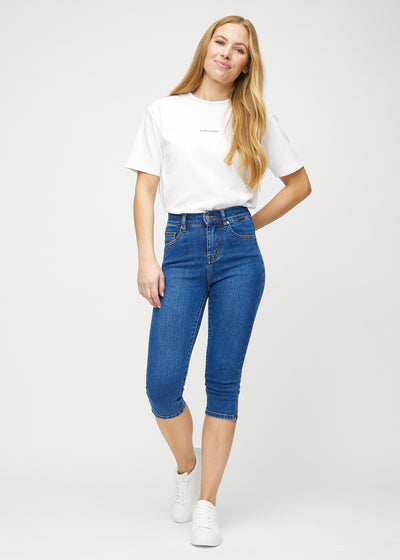 Fuldt billede af model i mørk denim skinny capris.