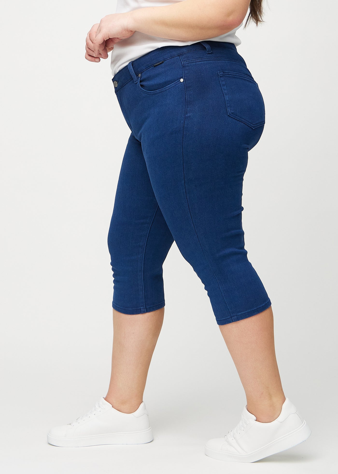 Mørkeblå skinny capris set fra siden på en plus-size model.