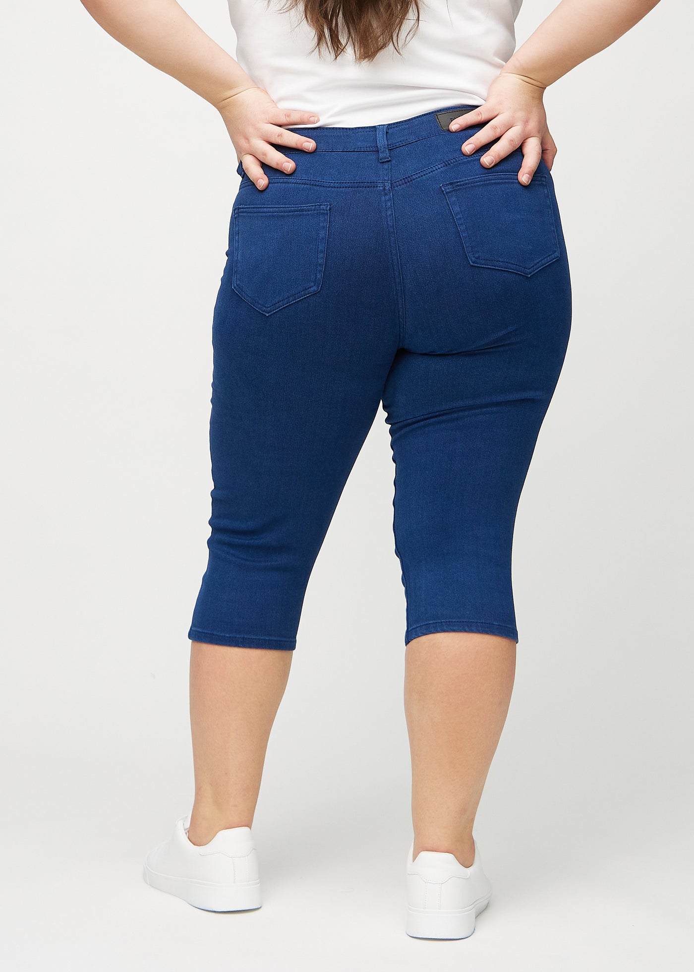 Mørkeblå skinny capris set bagfra på en plus-size model, så man kan se hele produktet.