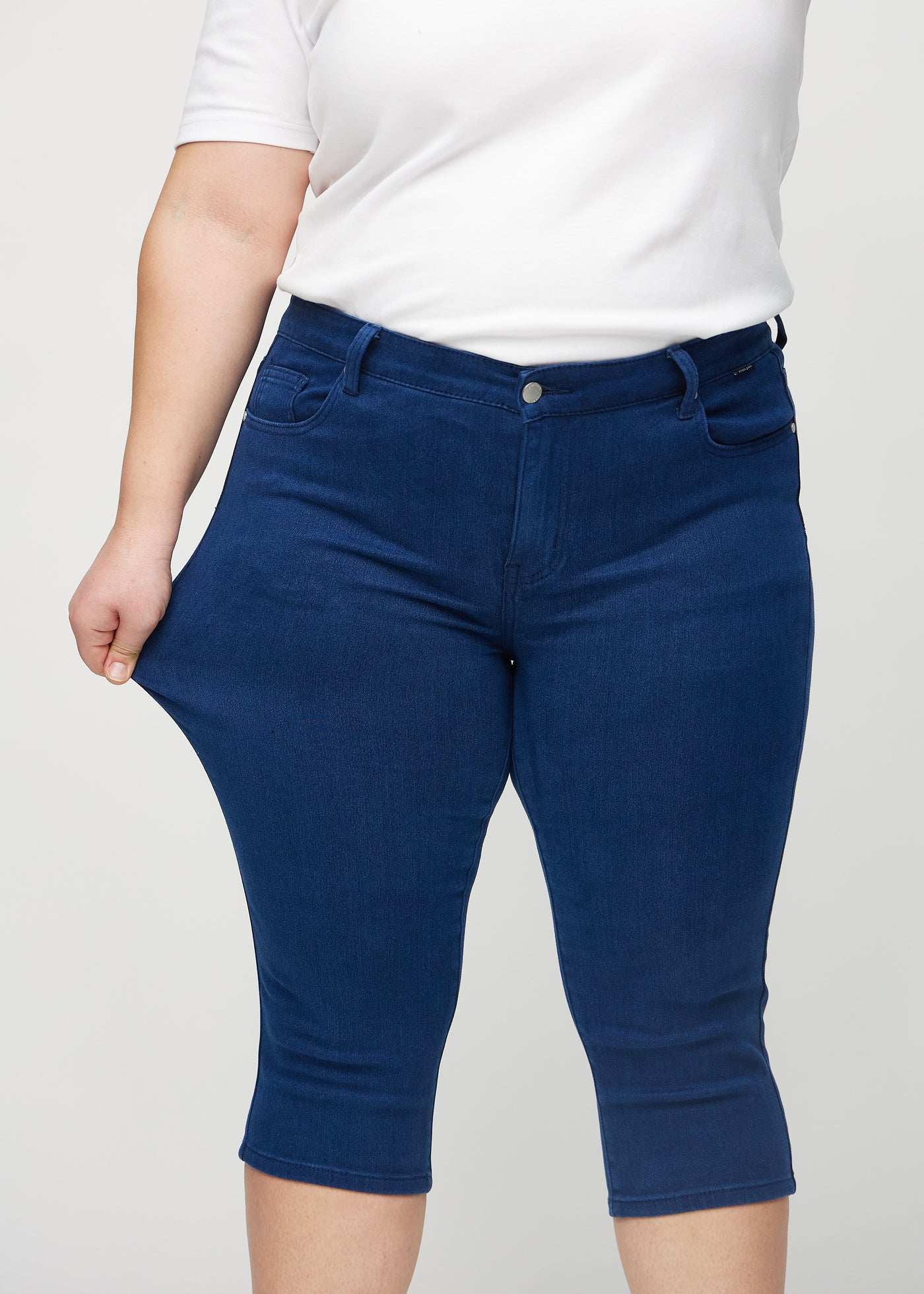 Plus-size model strækker caprisene ved låret for at vise stretch.