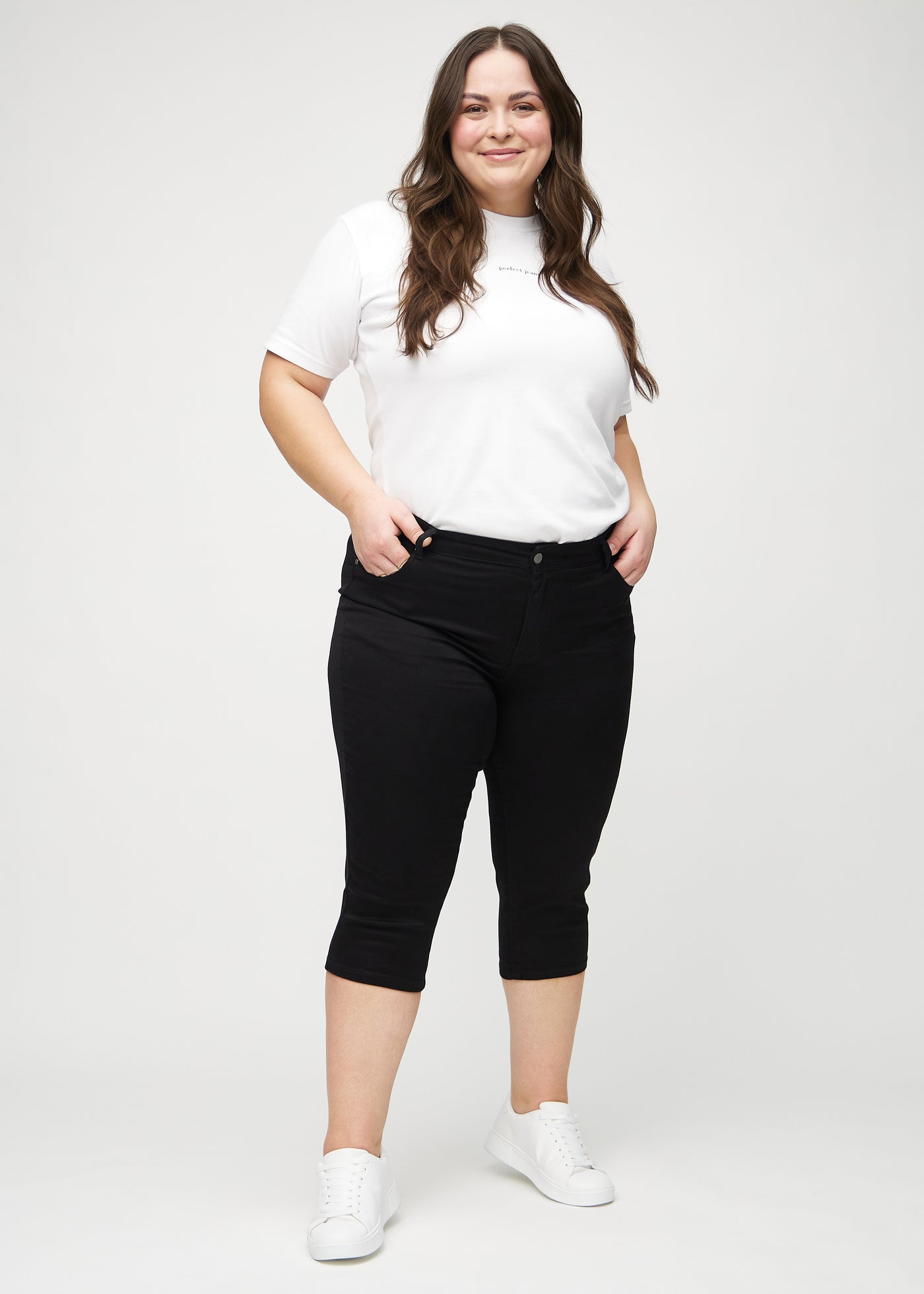 Fuldt billede af en plus-size model i sorte skinny capris.