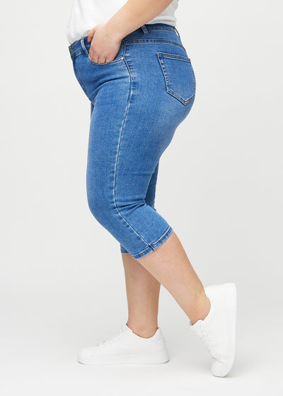 Denim skinny capris set fra siden på en plus-size model.