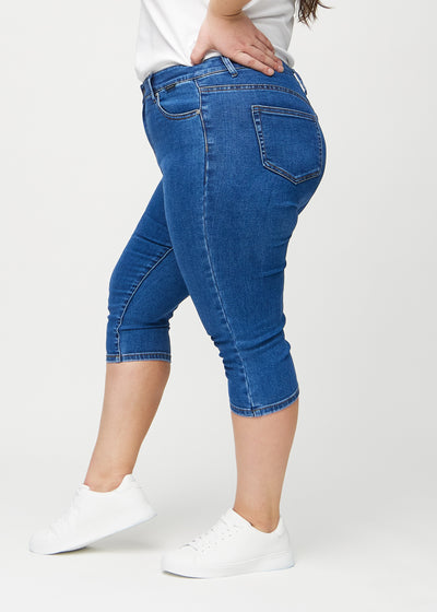 Mørk denim skinny capris set fra siden på en plus-size model.