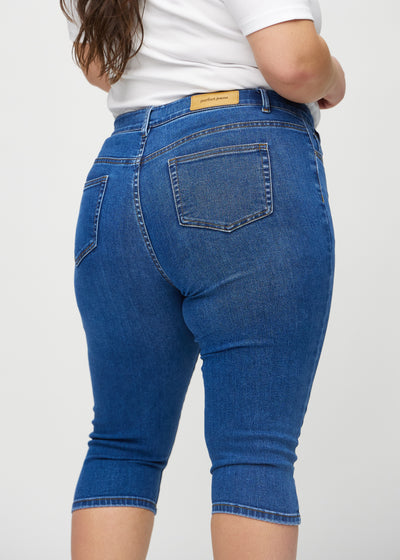 Mørk denim skinny capris set bagfra tæt på en plus-size model for at vise detaljer.