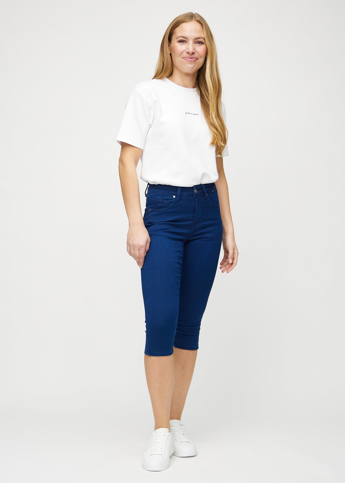 Fuldt billede af model i mørkeblå skinny capris.