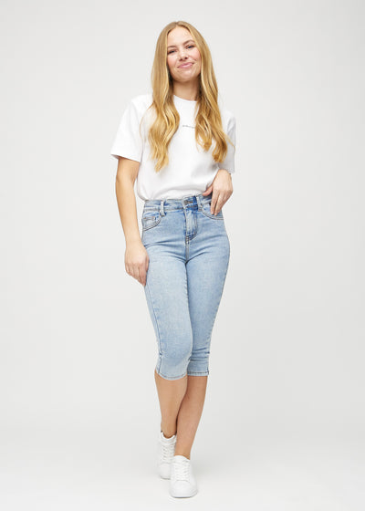 Fuldt billede af model i lys denim skinny capris.