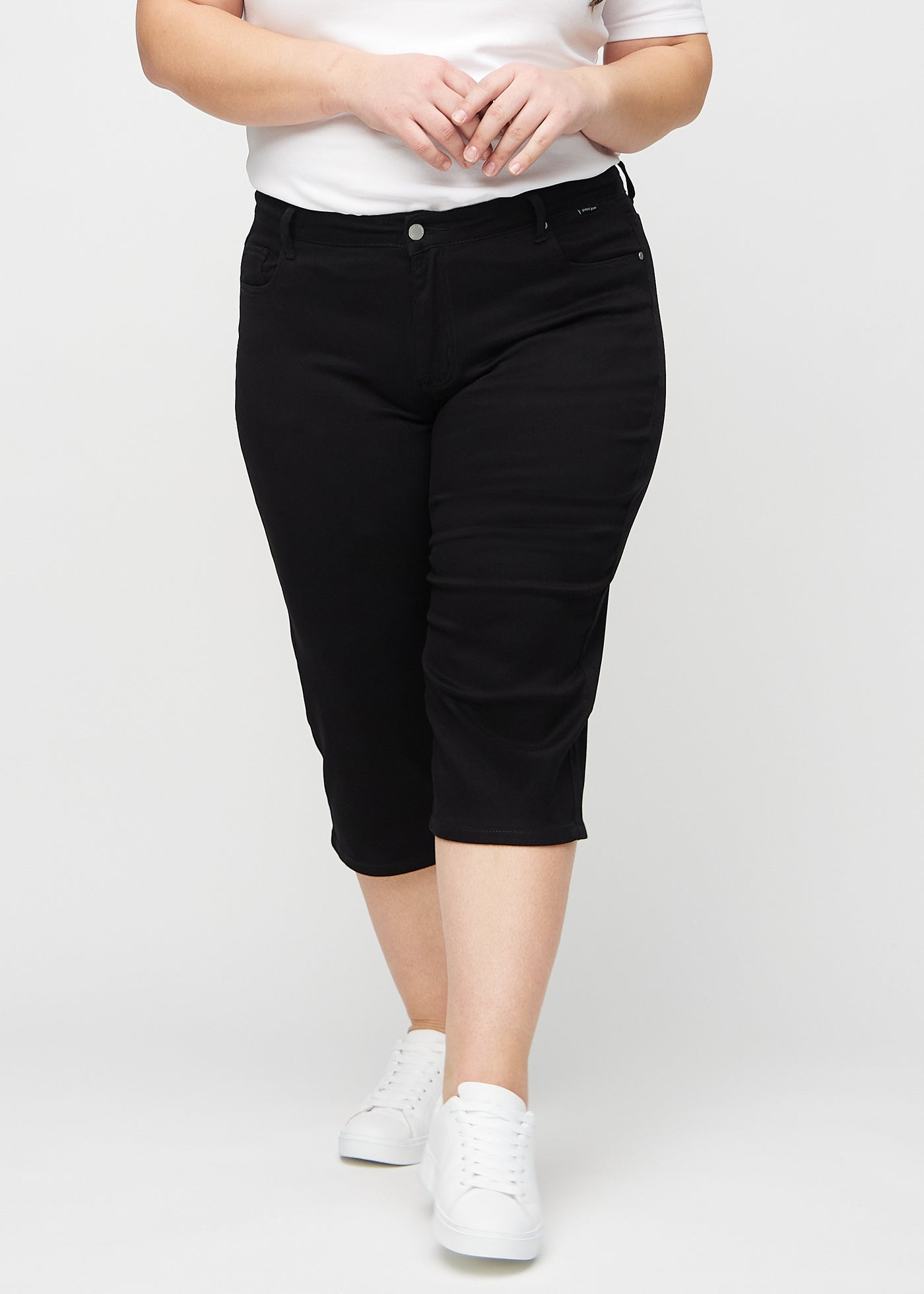 Sorte regular capris, modelnavn Ravens, som sidder lige til benet og slutter lige under knæet på en plus-size model, set forfra.