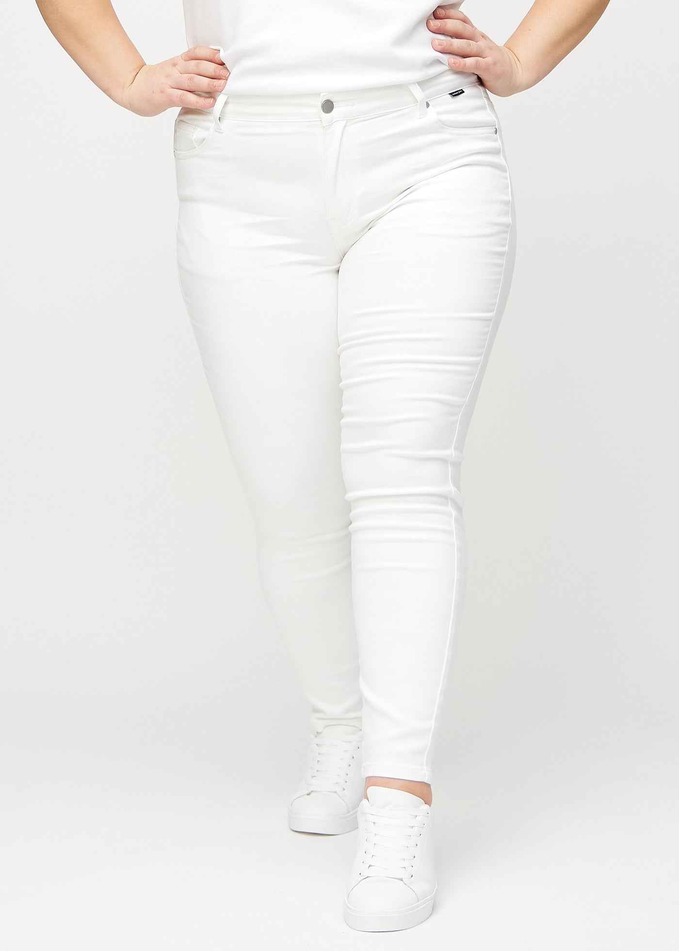 Hvide skinny jeans, modelnavn Marguerites, som sidder tæt til benet på en plus-size model, set forfra.