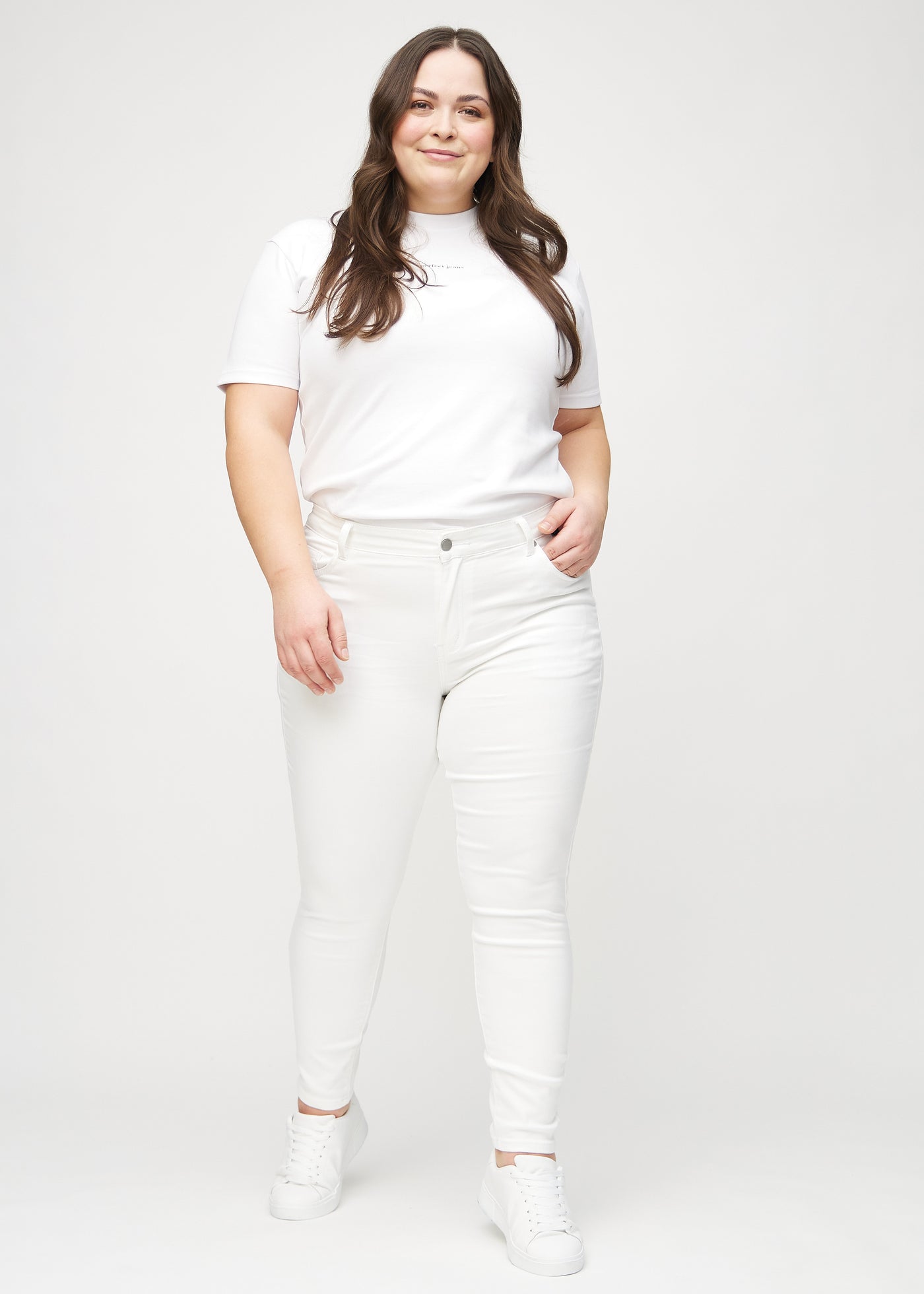 Fuldt billede af en plus-size model i hvide skinny jeans.