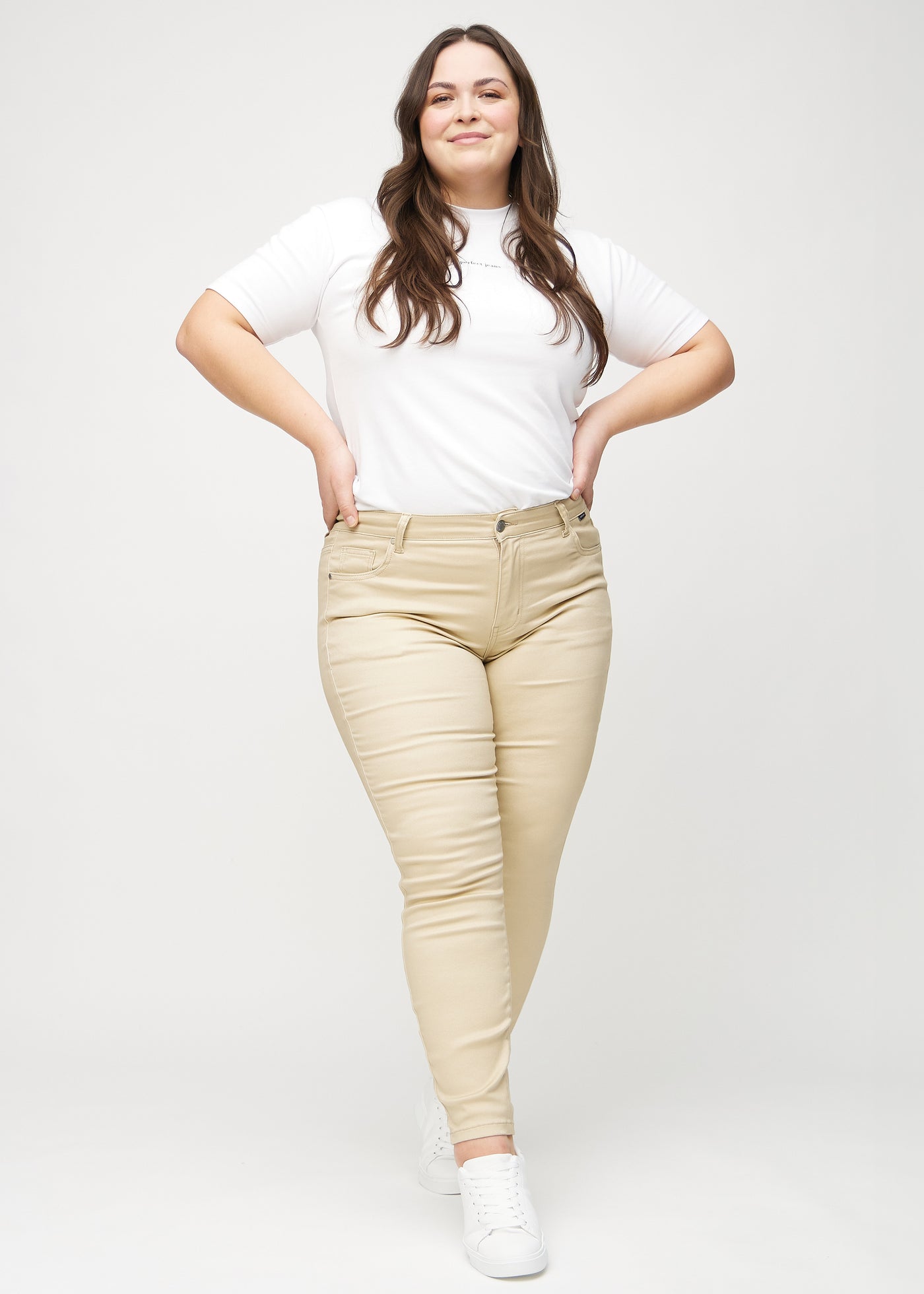 Fuldt billede af en plus-size model i beige skinny jeans.