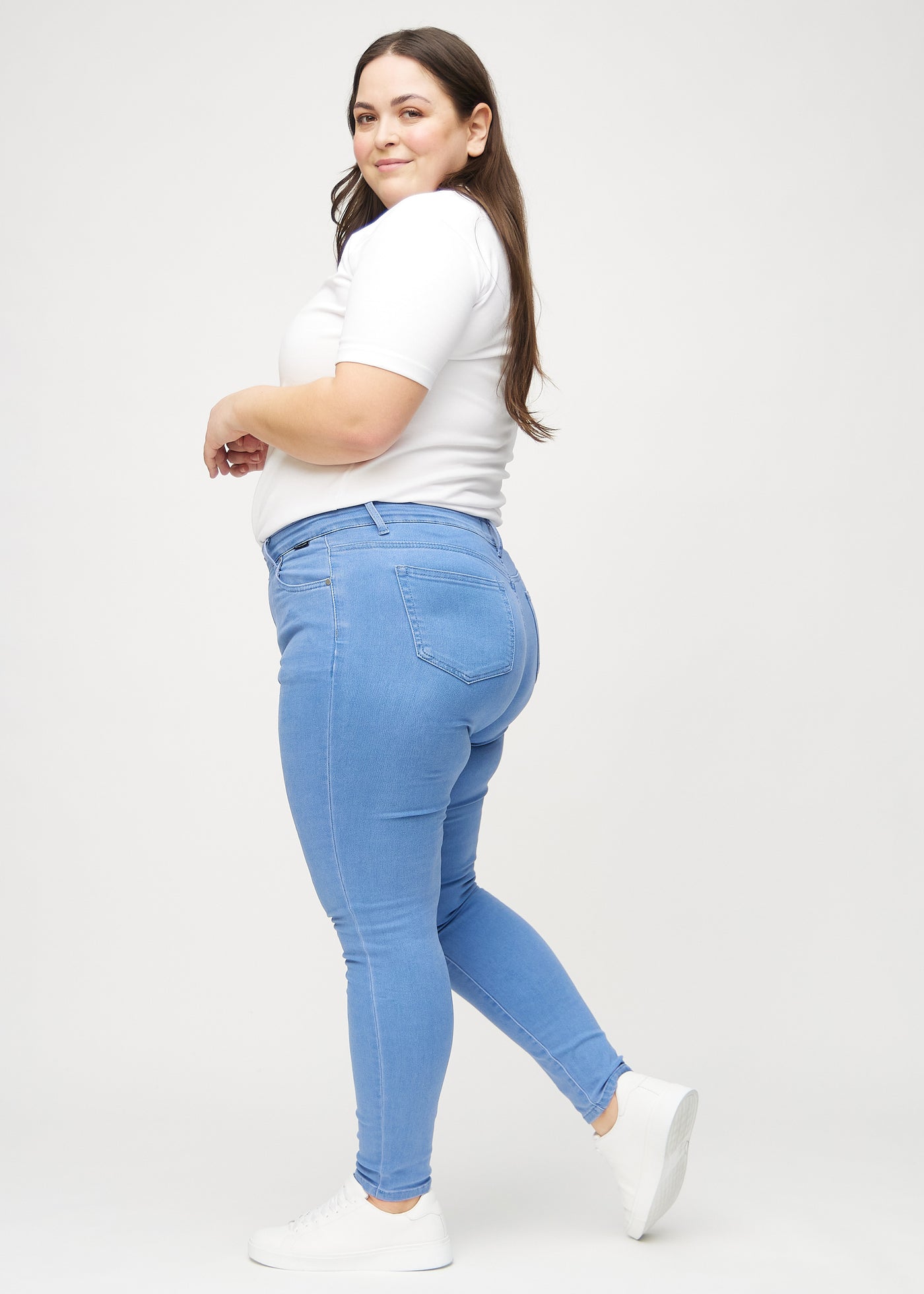 Blå skinny jeans set fra siden på en plus-size model.