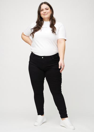 Fuldt billede af en plus-size model i sorte skinny jeans.