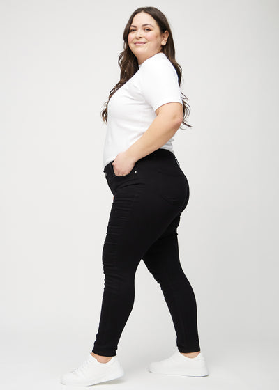 Sorte skinny jeans set fra siden på en plus-size model.