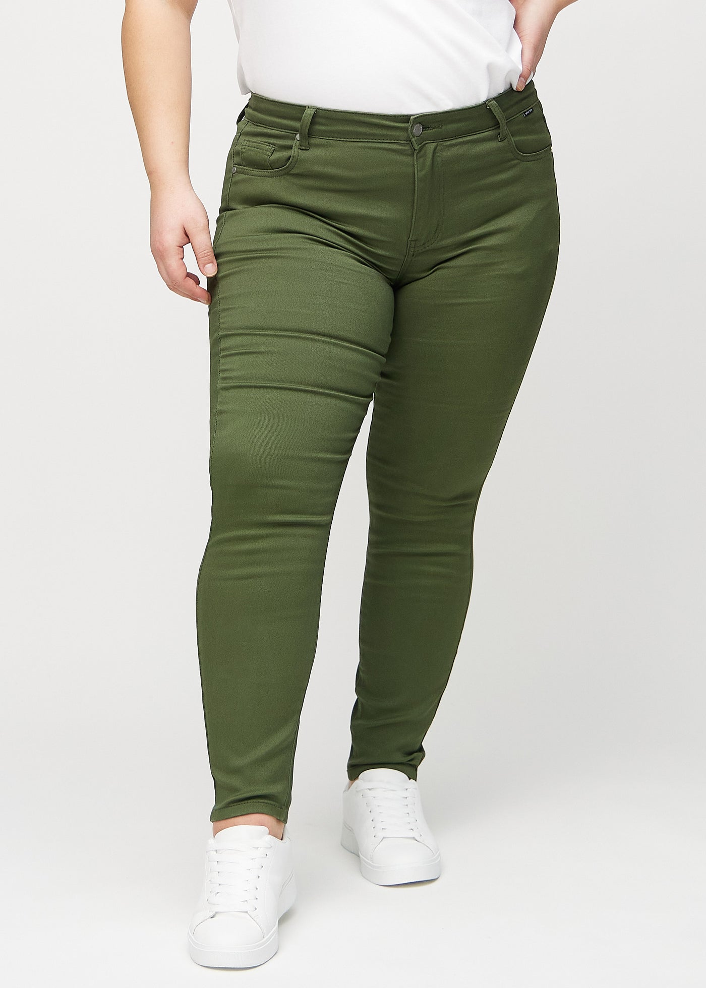 Mørkegrønne skinny jeans, modelnavn Renewals, som sidder tæt til benet på en plus-size model, set forfra.