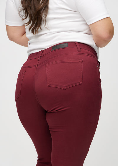 Mørkerøde skinny jeans set bagfra tæt på en plus-size model for at vise detaljer.