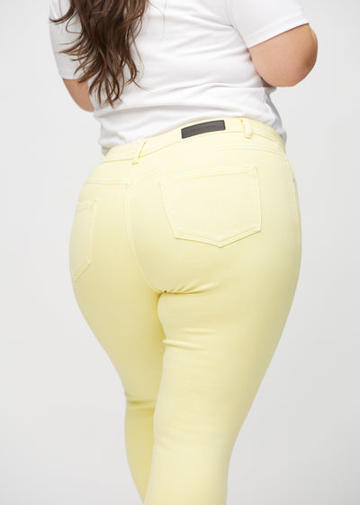 Lysegule skinny jeans set bagfra tæt på en plus-size model for at vise detaljer.