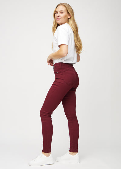 Mørkerøde skinny jeans set fra siden på model.