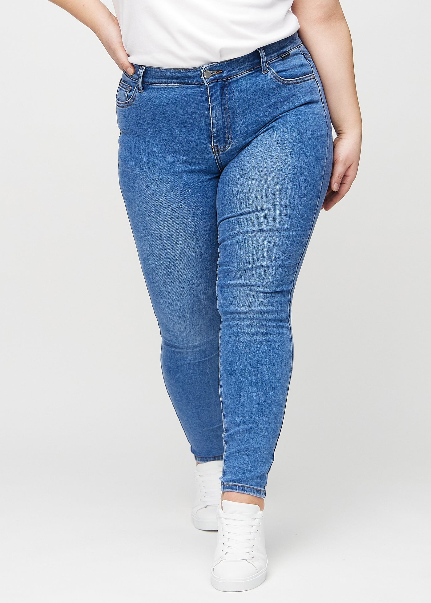 Denim skinny jeans, modelnavn Rivers, som sidder tæt til benet på en plus-size model, set forfra.