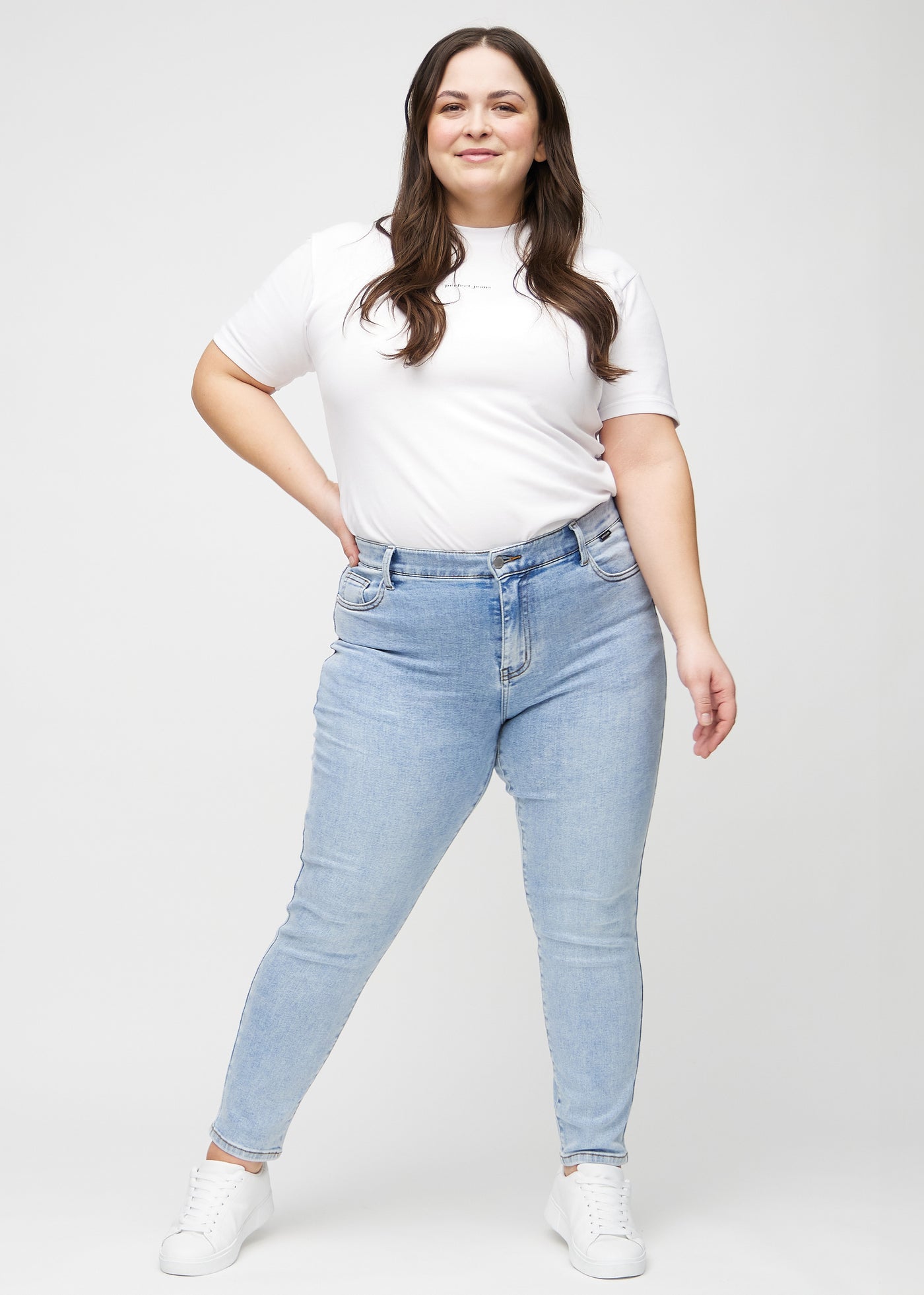 Fuldt billede af en plus-size model i lys denim slim ultra high rise jeans.