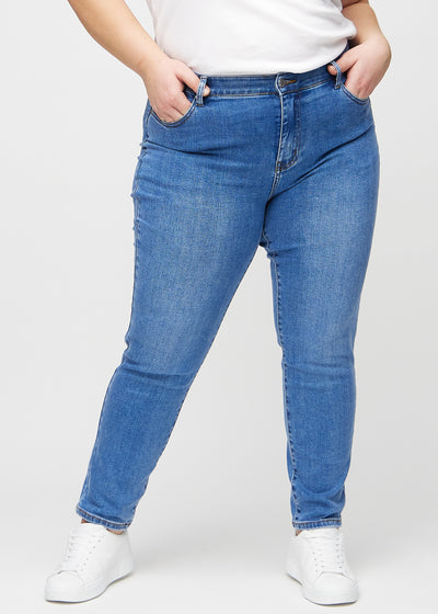 Denim slim jeans, modelnavn Rivers, som sidder tæt til benet, dog lidt løsere ved anklen, på en plus-size model, set forfra.