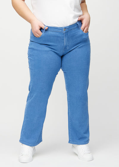 Blå loose jeans, modelnavn Geraniums, som er løstsiddende med masser af vidde i benene på en plus-size model, set forfra.