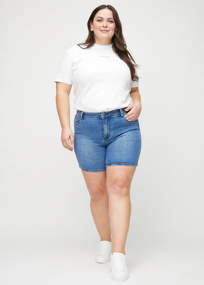 Plus-size model går ind i billedet, strækker i sine shorts, viser dem frem ved at dreje rundt, og forlader derefter billedet.