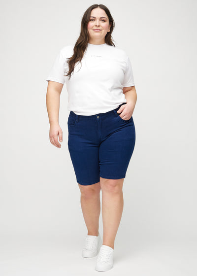 Plus-size model går ind i billedet, strækker i sine shorts, viser dem frem ved at dreje rundt, og forlader derefter billedet.