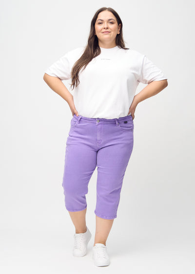 Plus-size model går ind i billedet, strækker i sine capris, viser dem frem ved at dreje rundt, og forlader derefter billedet.