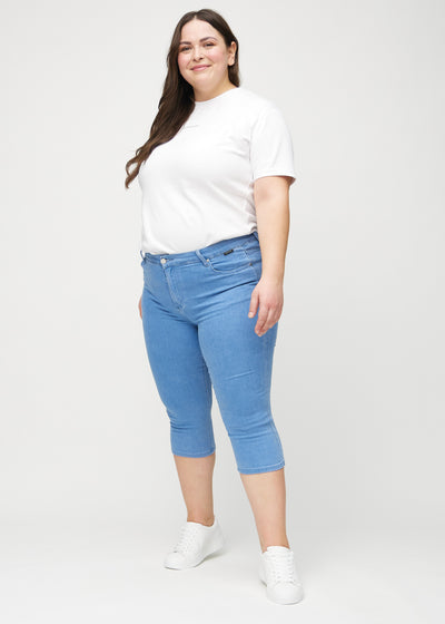 Plus-size model går ind i billedet, strækker i sine capris, viser dem frem ved at dreje rundt, og forlader derefter billedet.