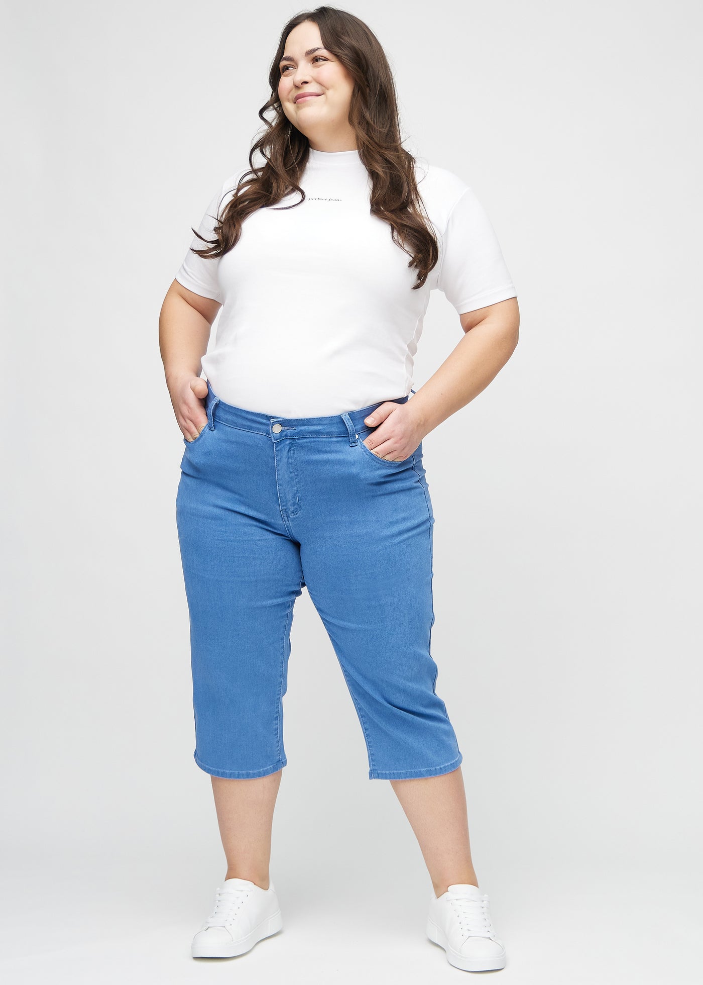 Plus-size model går ind i billedet, strækker i sine capris, viser dem frem ved at dreje rundt, og forlader derefter billedet.