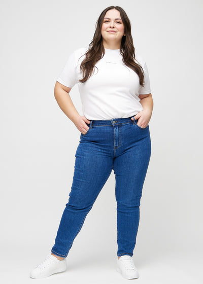 Plus-size model går ind i billedet, strækker i sine jeans, viser dem frem ved at dreje rundt, og forlader derefter billedet.