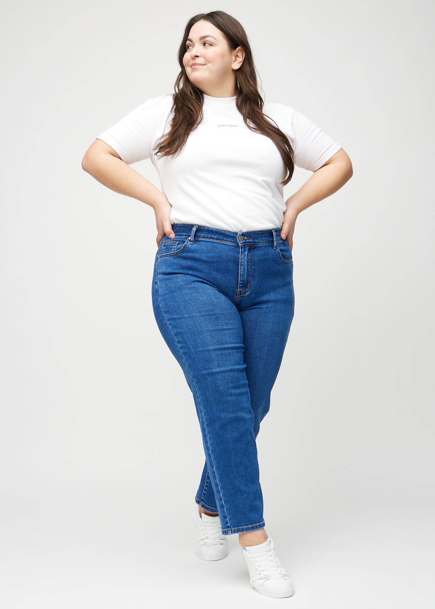 Plus-size model går ind i billedet, strækker i sine jeans, viser dem frem ved at dreje rundt, og forlader derefter billedet.