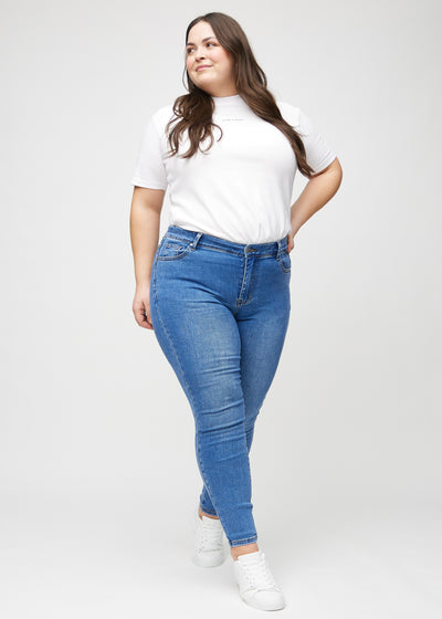 Plus-size model går ind i billedet, strækker i jeansene, viser dem frem ved at dreje rundt, og forlader derefter billedet.