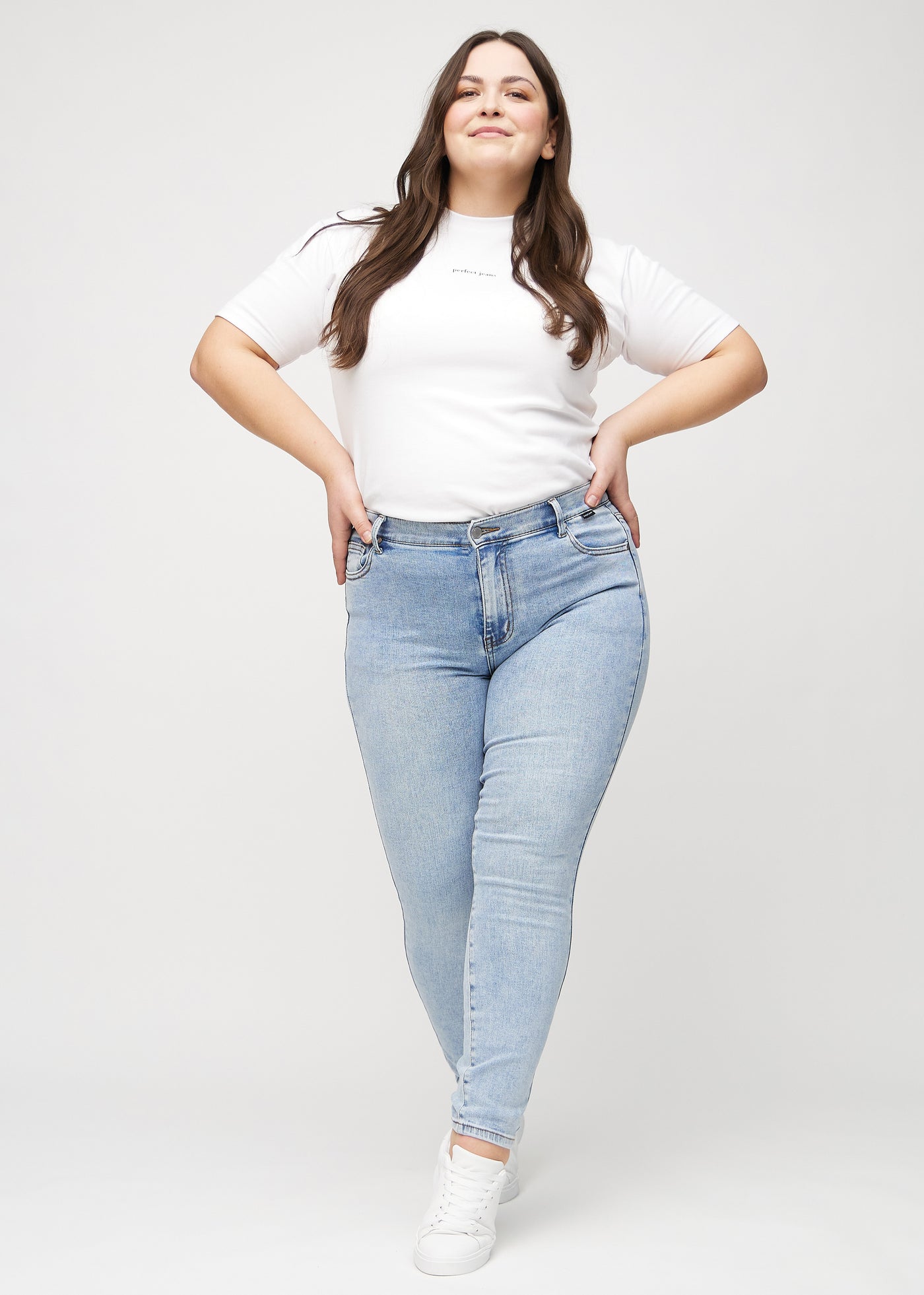 Plus-size model går ind i billedet, strækker i jeansene, viser dem frem ved at dreje rundt, og forlader derefter billedet.